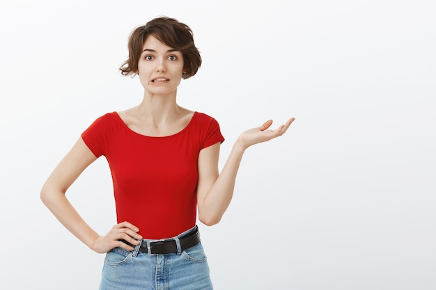 Foto gratuita giovane donna imbarazzante che alza la mano confusa e che sembra incapace