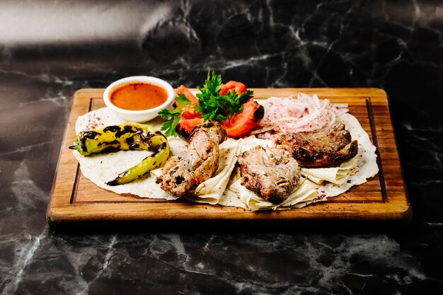 Azerbaijani beef barbecue kebab served on lavash with grilled pepper, tomatoes and bbq sauce.