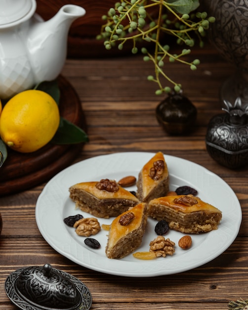 Azerbaijani dessert pakhlava with nuts and sultana inside white plate.