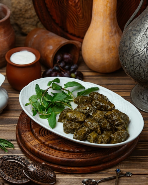 Free photo azerbaijani dolma grape leaves wraps with meat, rice served with yoghurt