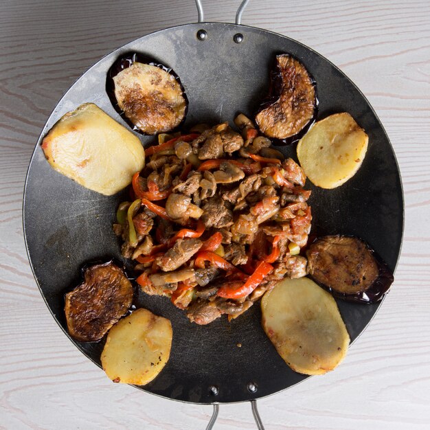 Azerbaijani sac ichi in a black pan with mixed foods.