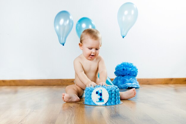 Baby boy celebrating her first birthday with gourmet cake and ba