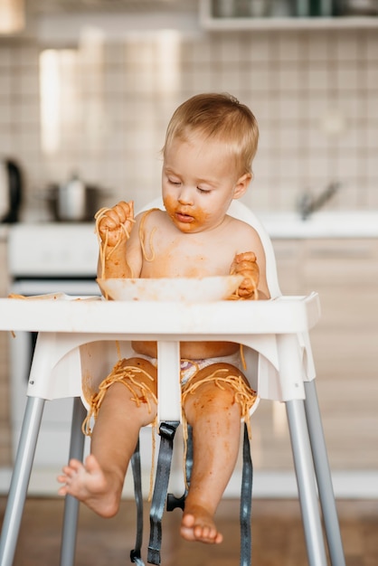 Baby boy eating pasta with his hands