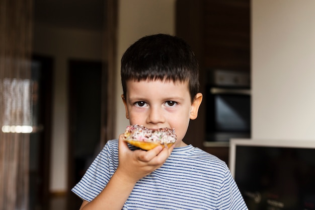 Baby boy having sweet doughnut at home
