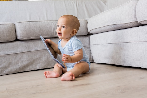 Baby boy playing with digital tablet in living room