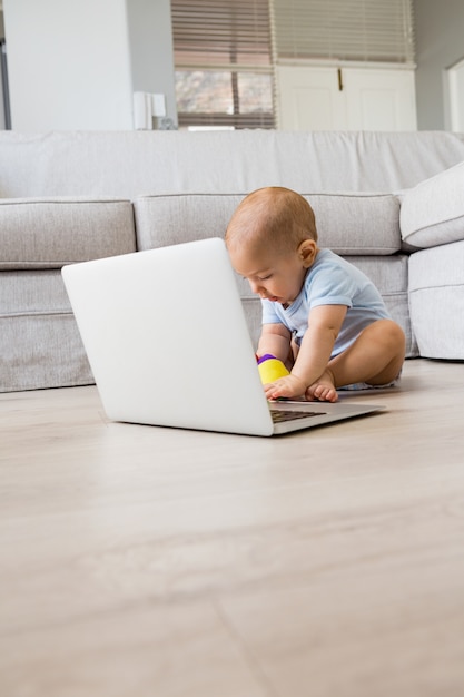 リビングルームにノートパソコンで遊んで赤ちゃんの男の子