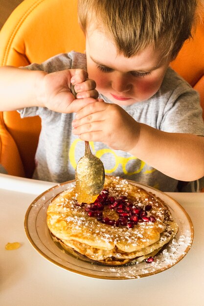 Baby boy putting jam over the pancake