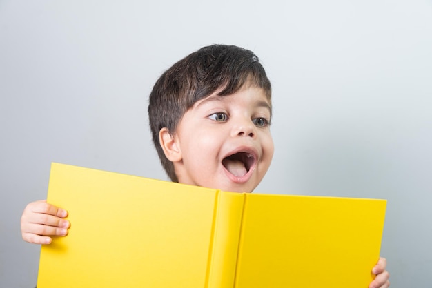 Free photo baby boy reading yellow book