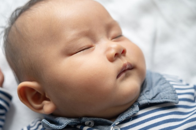 Free photo a baby boy in a striped shirt is sleeping in bed.