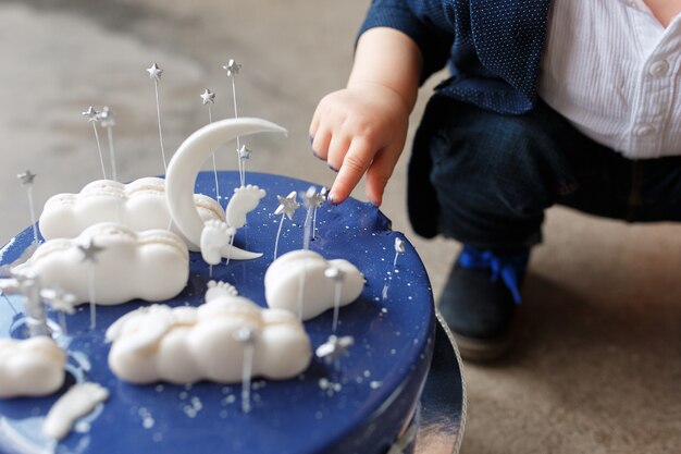 彼の指で誕生日のケーキに触れる赤ん坊の少年。最初のケーキスマッシュコンセプト