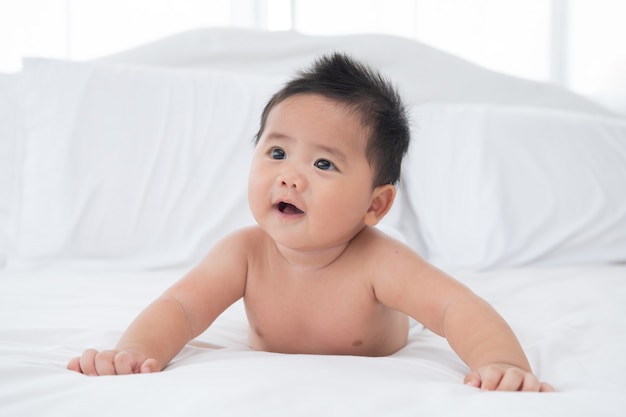 하얀 햇볕이 잘 드는 침실에서 기저귀를 차고 있는 아기