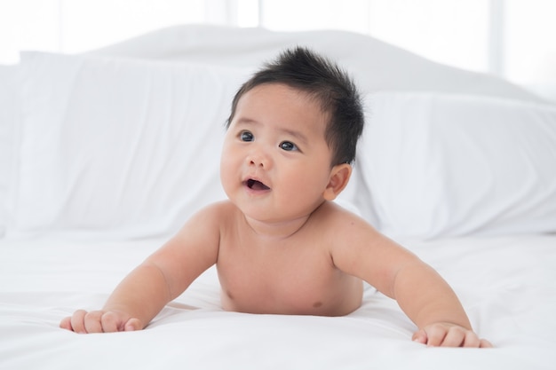 Free photo baby boy wearing diaper in white sunny bedroom