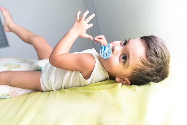 Baby boy in white tshirt lying on bed