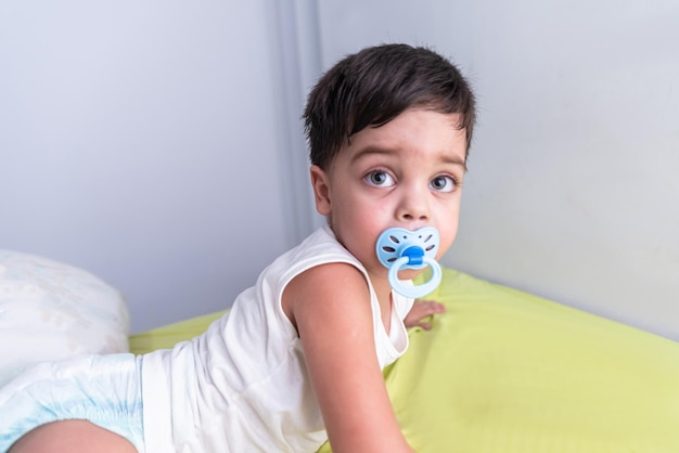 Free photo baby boy in white tshirt lying on bed