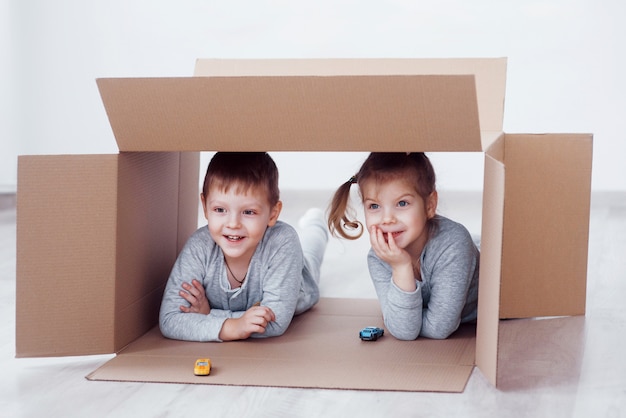 Baby brother and child sister playing in cardboard boxes in nursery