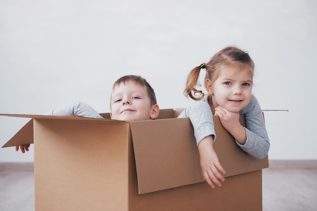 Baby brother and child sister playing in cardboard boxes in nursery