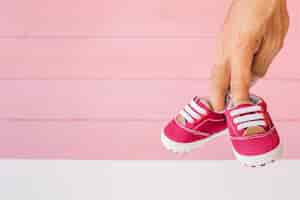 Free photo baby concept with fingers holding shoes