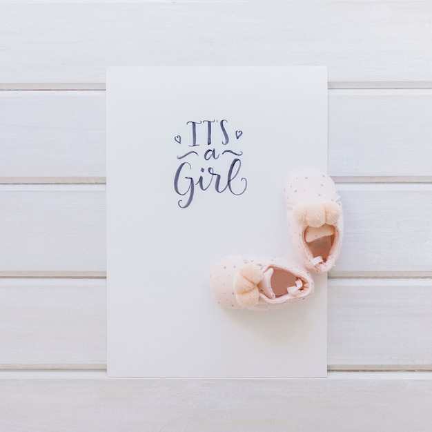 Baby concept with paper and shoes on wooden surface