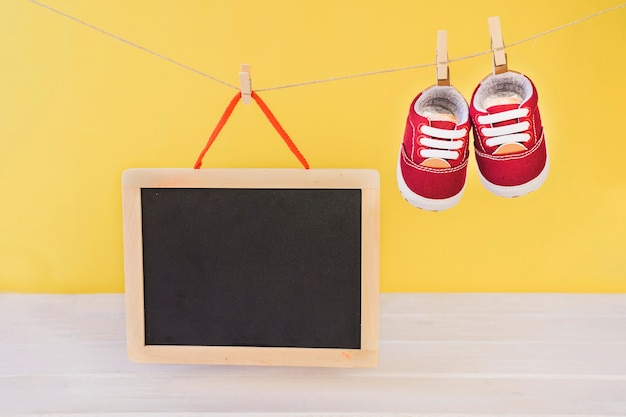 Foto gratuita concetto di bambino con ardesia e scarpe appesa sul clothesline