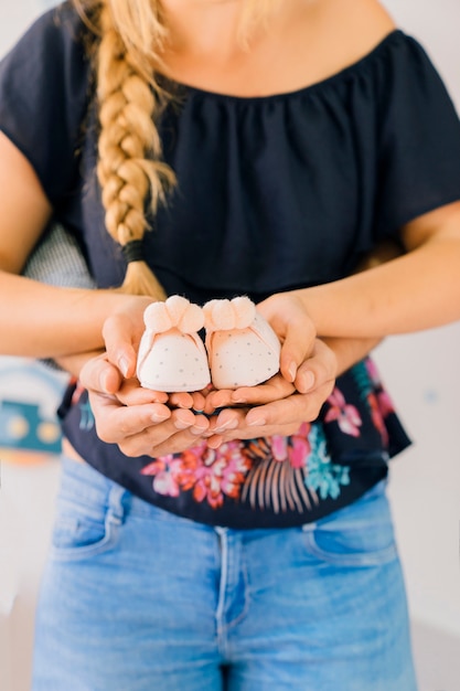 Baby concept with young woman holding baby shoes