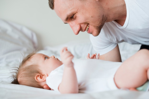 Baby and dad looking at each other in bed
