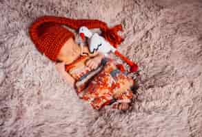 Free photo baby enveloped in red scarf sleeps on fluffy blanket