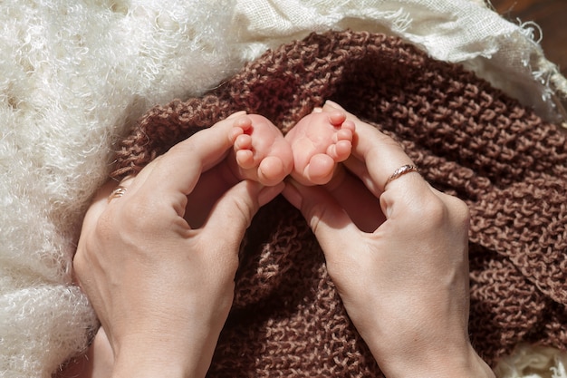 어머니 손에 아기 발. 여성 모양의 손 근접 촬영에 작은 신생아의 발. 엄마와 그녀의 아이. 행복한 가족 개념입니다. 출산의 아름다운 개념적 이미지