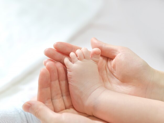 母親の手で赤ちゃんの足。