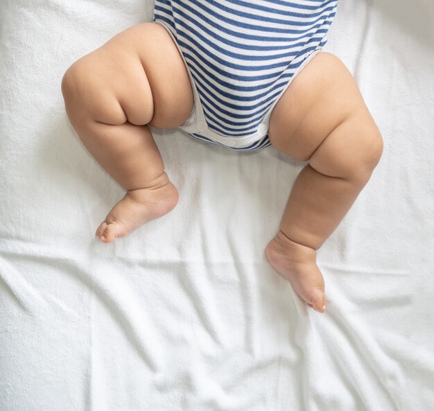 Baby feet in white bed.