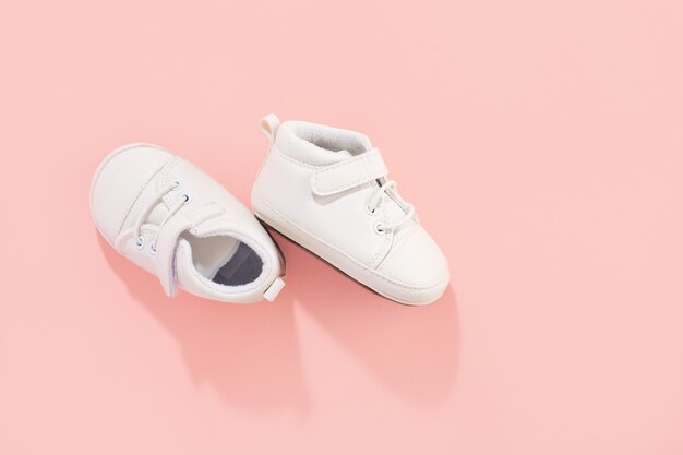 Baby first shoes on pink pastel background. Family or motherhood concept.