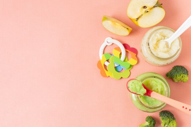 Baby food in jars on pink background