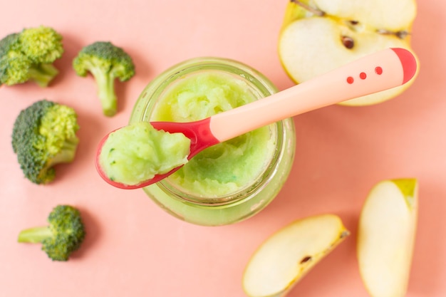 Baby food on pink background flat lay