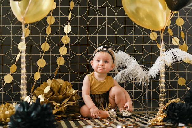 Baby girl birthday party decorated with black and golden balloon. 