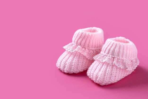 Baby girl booties on pink background Copy space