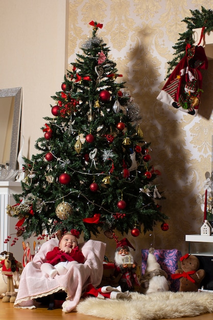 baby girl under christmas tree with stuffed toys