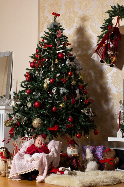 ぬいぐるみのクリスマスツリーの下の女の赤ちゃん