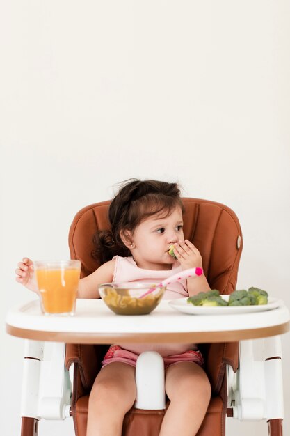 子供の椅子で食べる女の赤ちゃん