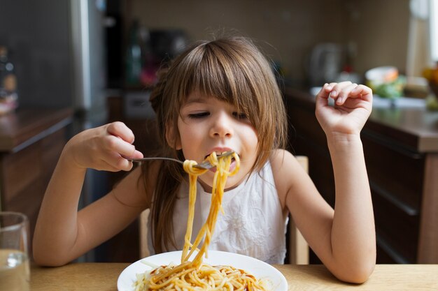 Baby girl having pasta dish indoor