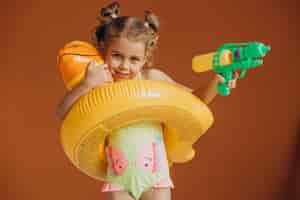 Free photo baby girl isolated wearing swimsuit and rubber duck tube and holding water pistol