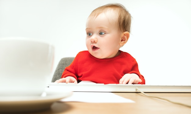 Free photo baby girl sitting with cup of coffee and keyboard