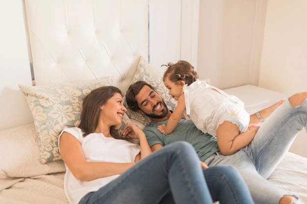 Baby girl spending time with parents on bed