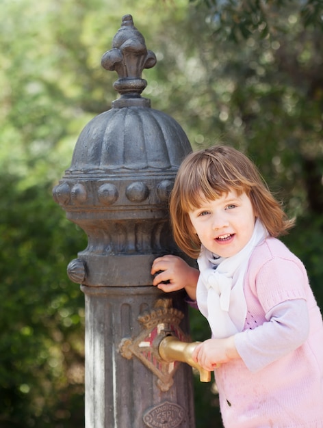 Baby girl using water pump on street of Barcelona