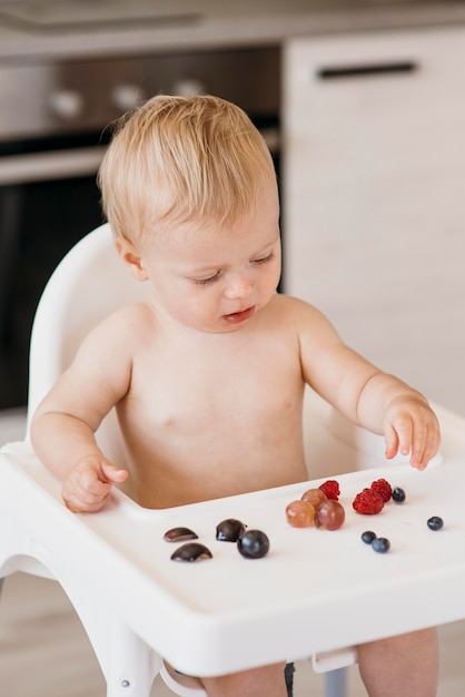 Baby in highchair choosing what fruit to eat