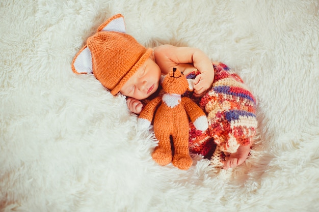 Baby holds little fox toy sleeping on the white pillow 