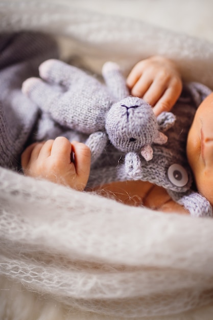 Ребенок держит игрушечную корову, лежащую на пушистой подушке
