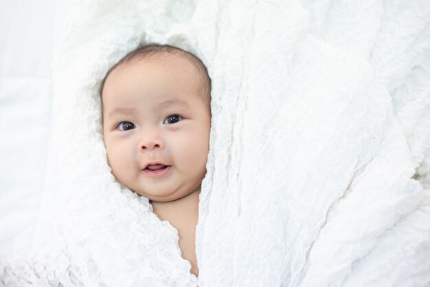 The baby is happy on the bed.