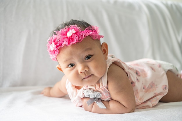 The baby is lying face down on the bed.