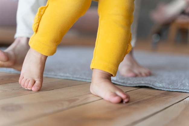 Foto gratuita il bambino impara a camminare e viene aiutato da sua madre