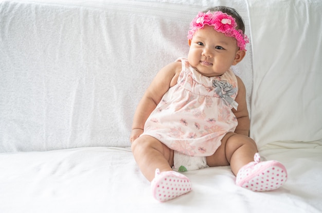 A baby learns to sit on a white bed