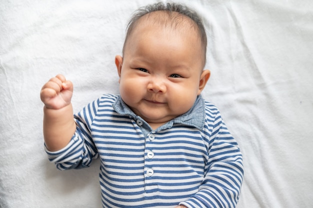 白いベッドの上に仰向けになって赤ちゃん